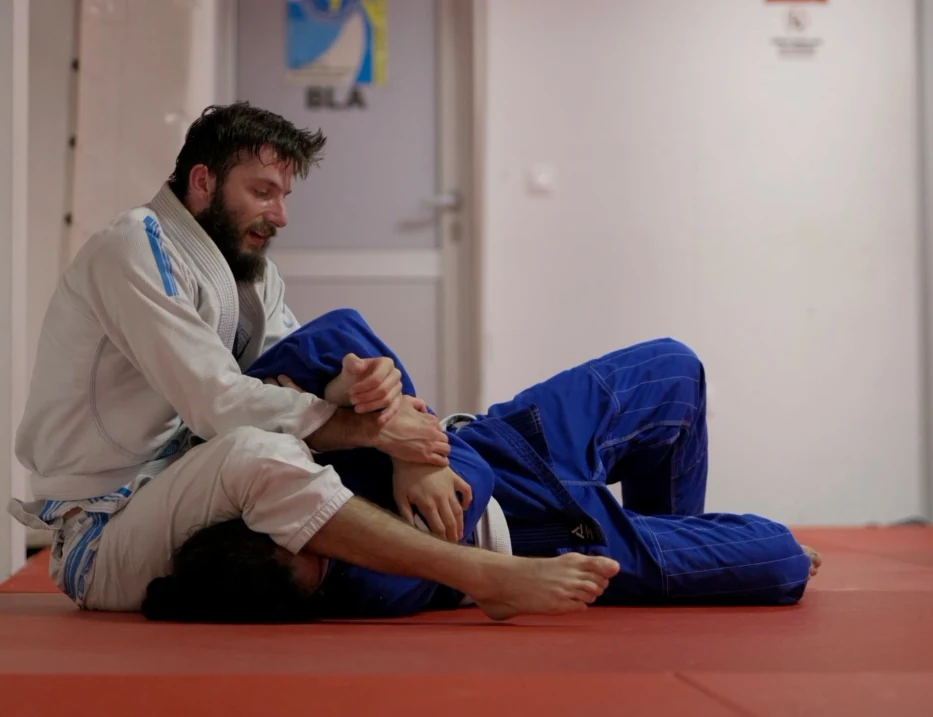 Dvojica partnera u bijelom i plavom kimonu vježbaju armbar iz gornje kontrole